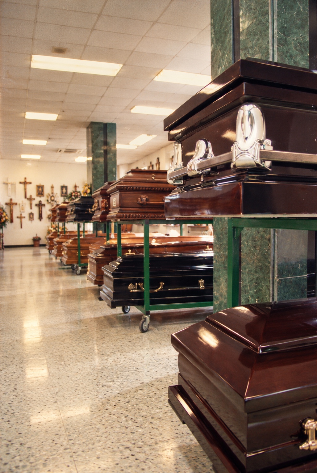 Sala de la Funeraria Municipal con urnas de madera pulida y crucifijos en la pared