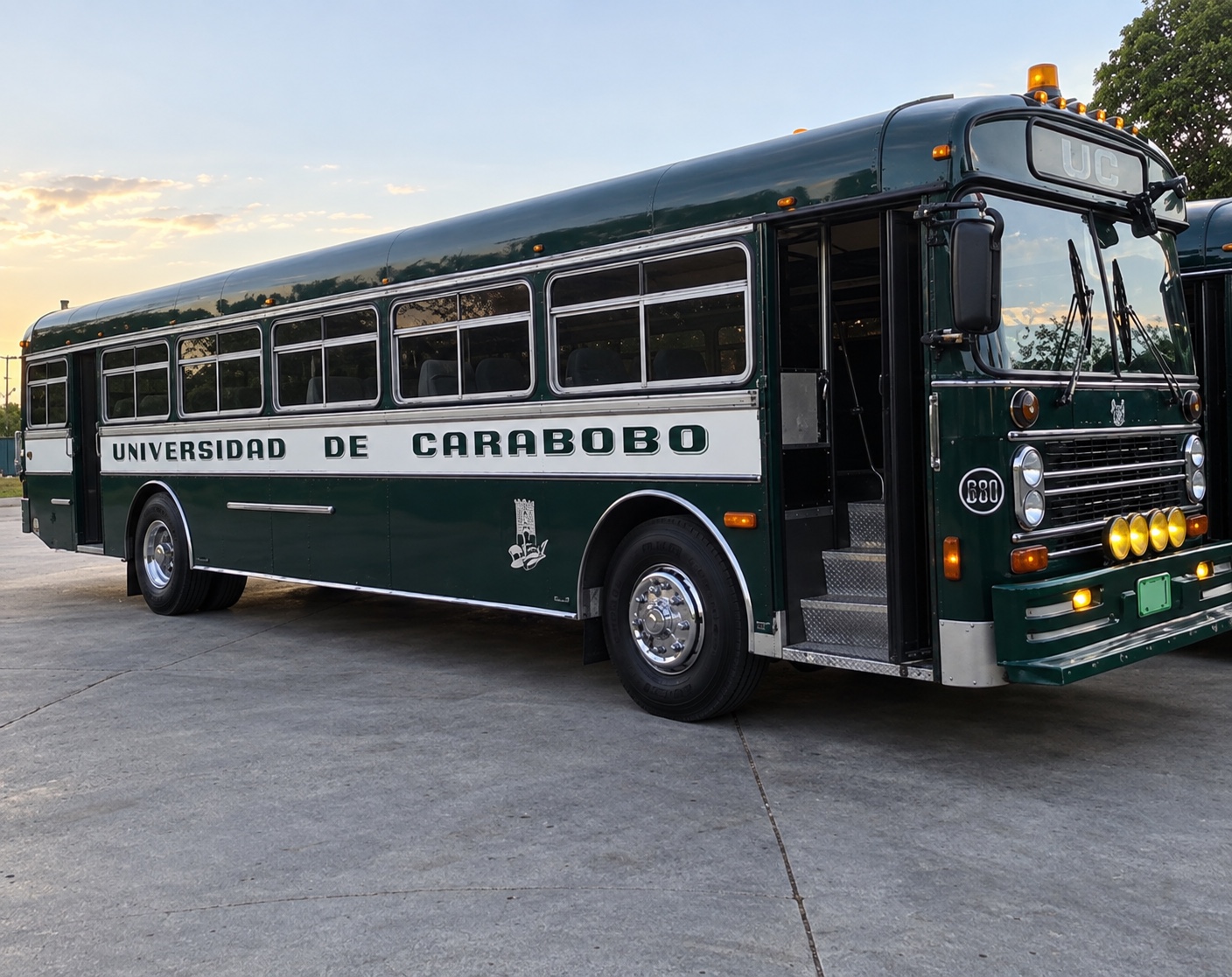 Autobús verde y blanco de la Universidad de Carabobo estacionado al atardecer