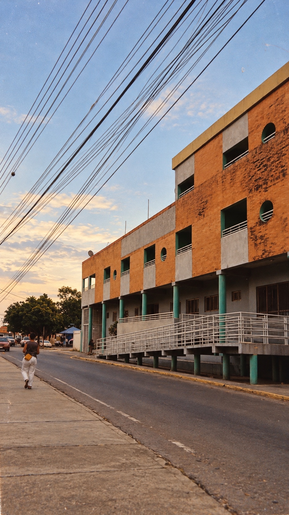 Edificio del Gran Palacio Municipal de Guacara, de ladrillo naranja y gris con columnas verdes y ventanas circulares, junto a la calle al atardecer